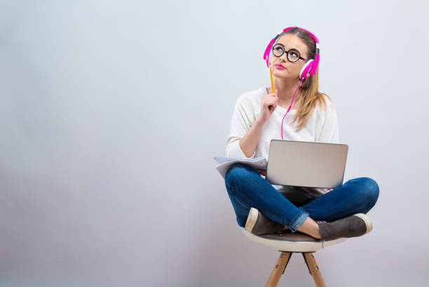 Young woman studying on her laptop computer on a gray background