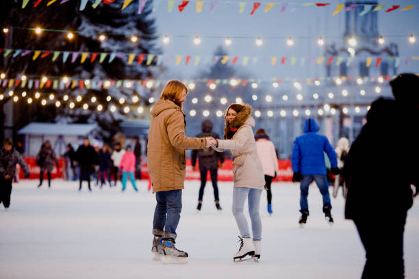 白人の愛の若いカップル男長い髪のブロンドの髪、ひげと美しい女性クリスマスイブに冬にスケートに町の広場でアイスのシーンで楽しく、アクティブな日 - ice float ストックフォトと画像
