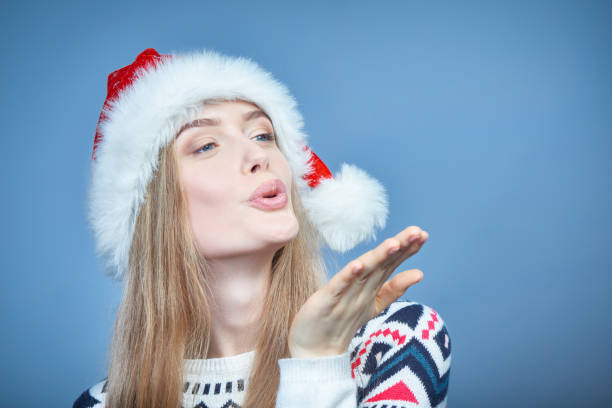 istock Woman wearing Santa hat blowing at open hand palm with copy space 1084974698
