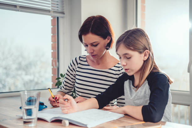 istock Mother helping daughter to finish homework 1084981152