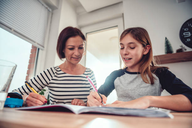 istock Mother helping daughter to finish homework 1084981848