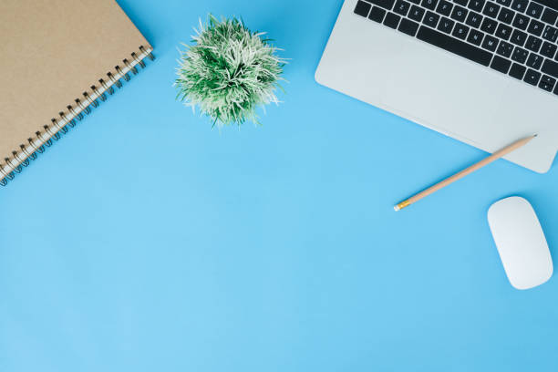 istock Minimal work space - Creative flat lay photo of workspace desk. Top view office desk with laptop, notebooks and coffee cup on blue color background. Top view with copy space, flat lay photography. 1084985640