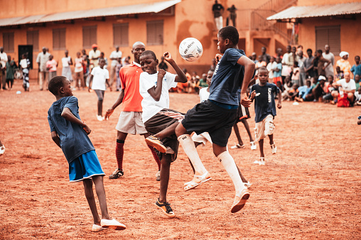 Mali, Africa - Black african children, boys and adults playing soccer in a rubbish dump. Rural area near Bamako