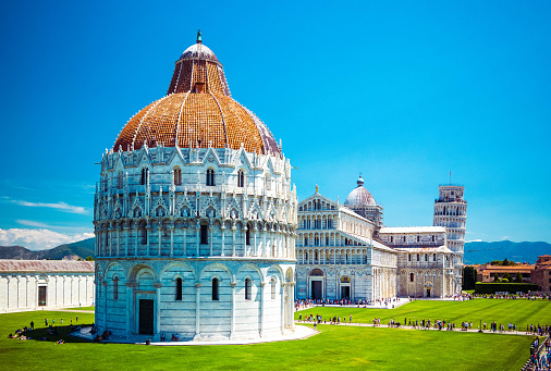 Baptistery of St. John on Square of Miracles, Leaning Tower, famous inclined tower of Pisa with green lawn in Pisa, Tuscany, Italy.