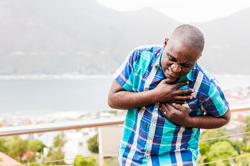 An african male person having a sudden pain in the chest in the Cape town area of South Africa, while an african guy is trying to help him.