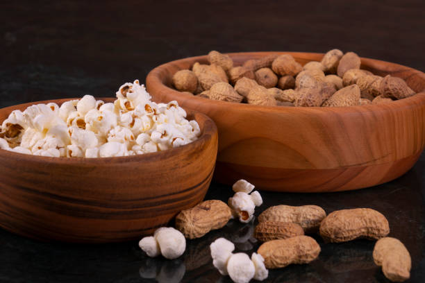 arachides avec popcorn dans le bol en bois doré sur table de marbre noir - baseball baseballs peanut american culture photos et images de collection