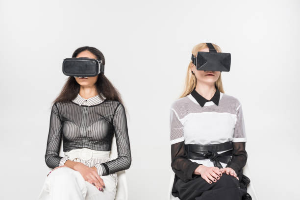 istock attractive multiethnic women using virtual reality headsets sitting on chairs isolated on white 1084998582