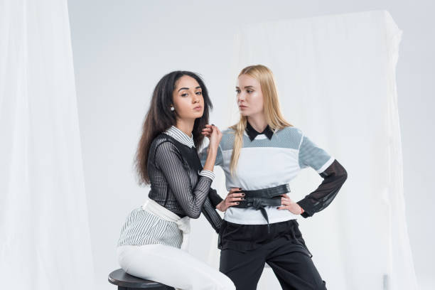 istock attractive multiethnic women in black and white clothes posing on chairs on white 1085003320