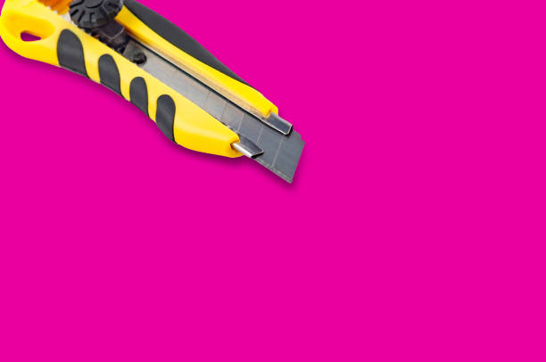 istock Stationery knife with yellow and black plastic handle on pink background with copy space for your text 1085006874