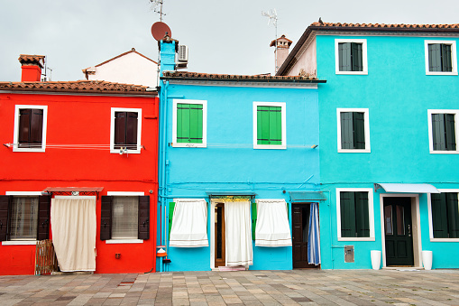 Fronts of the bright red, blue and turquoise houses on the island of Burano, Venice, Italy, travel