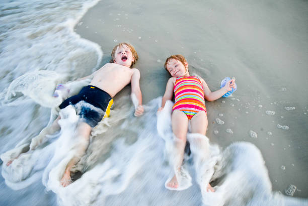 children play in the ocean stock photo