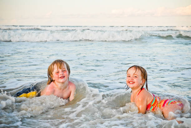 children play in the ocean waves stock photo