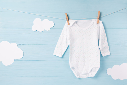 Ropa de bebé y nubes blancas sobre un fondo de tendedero, azul photo