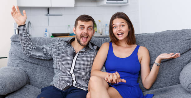 istock Smiling young couple sitting on sofa at home watching TV 1085024196