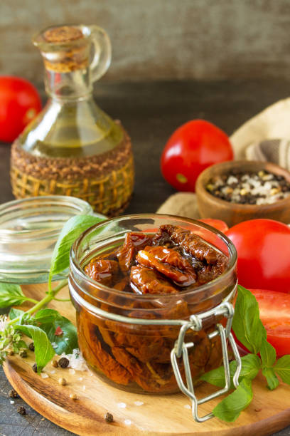 istock Sun dried tomatoes with olive oil in a jar on black stone or concrete table. Copy space. 1085024700
