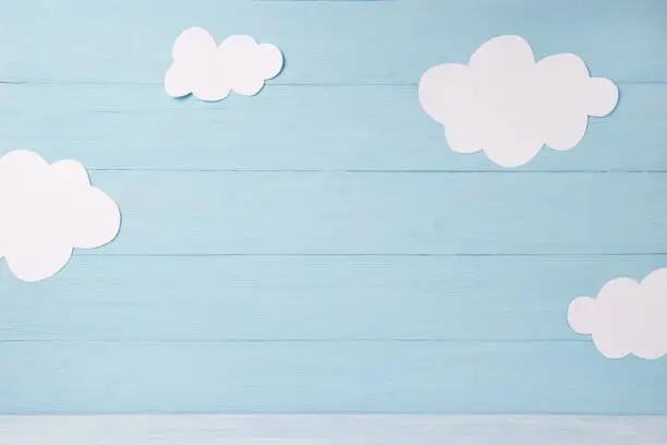 Photo of Cute children or baby card, white clouds on the blue wooden background