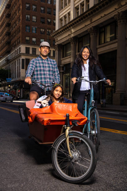 familj ridning cyklar och leende på kamera - parents children cargo bike bildbanksfoton och bilder