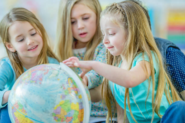 istock Kindergarten kids looking at a globe 1085027364