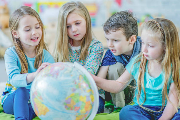 istock Kindergarten kids looking at a globe 1085027372