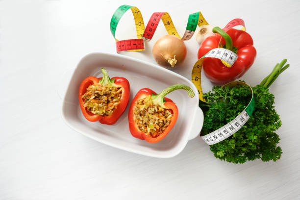 istock stuffed red bell pepper in a baking casserole, measure tape and ingredients on a white table, diet concept, copy space, high angle view from above 1085028990
