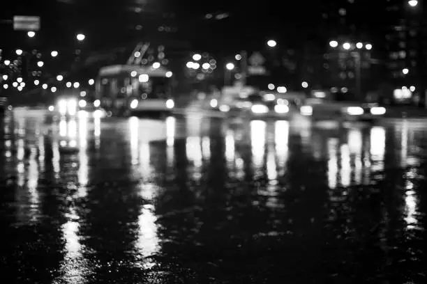 Photo of Rainy city road at night. Defocused black and white image