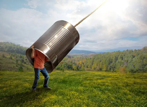 A man listens to the sounds from above with a tin can.