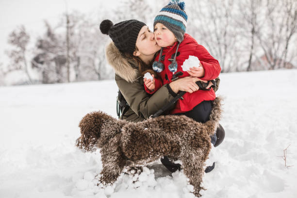 Mother with dog and son having fun at snow on a winter day