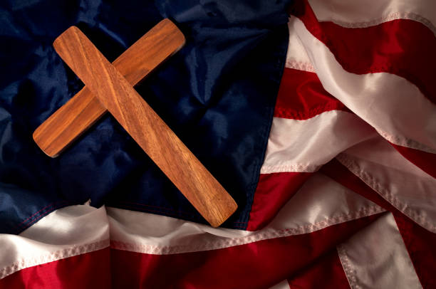福音主義のアメリカ、キリスト教と再びキリスト教および根本主義者の宗教右の概念を生まれは木製の十字架や劇的な光と不機嫌な口調でアメリカの国旗に十字架にクローズ アップ - right wing ストックフォトと画像