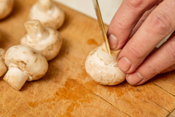 istock Hand with knife cuts champignons on the board in the kitchen 1085069408