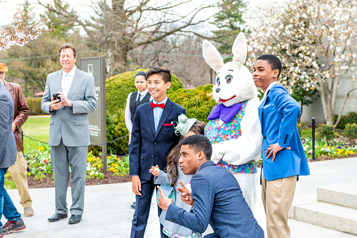 Washington DC, USA - April 1, 2018: People taking photo, picture, photographing with Easter bunny costume person at basilica of National Shrine of Immaculate Conception Catholic church