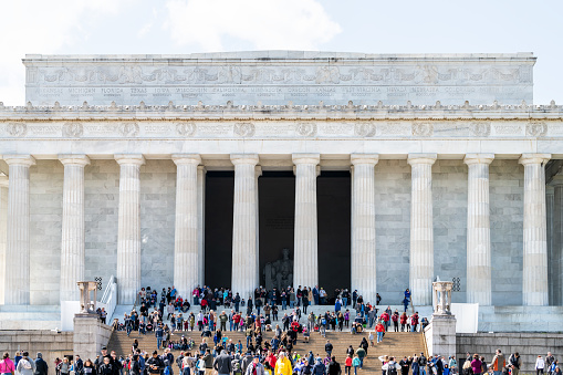 Washington DC, USA - April 5, 2018: People, tourists walking at stairs, steps, staircase of Lincoln Memorial front, facade at spring season, at National Mall park, columns, taking photos, pictures