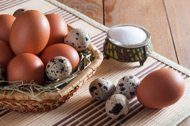 istock Several large brown chicken eggs and some small mottled quail eggs on straw in wicker basket. Near three quail eggs, one chicken egg and salt in salt shaker. 1085076692