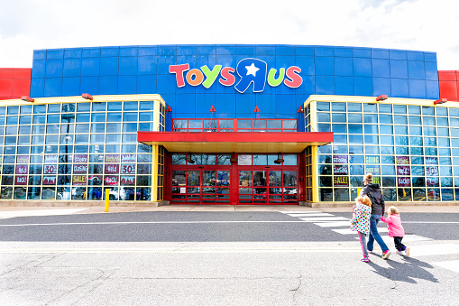 Fairfax, USA - April 5, 2018: Toys R US store shop, Virginia, entrance, promotion, advertising signs, logo, doors, closing going out of business bankruptcy, mother, children, family walking