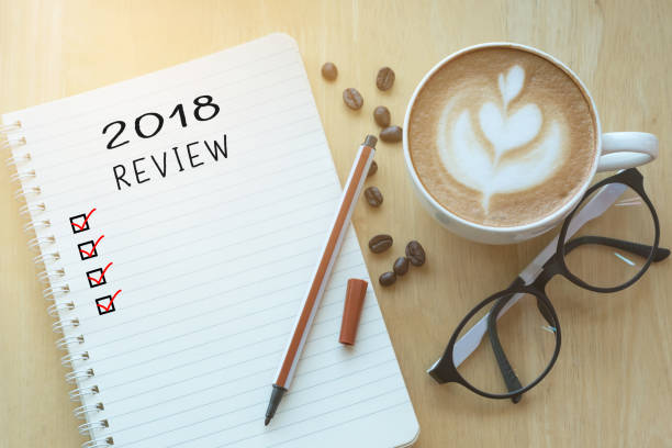 istock 2018 review message on notebook with glasses, pencil and coffee cup on wooden table. 1085080052