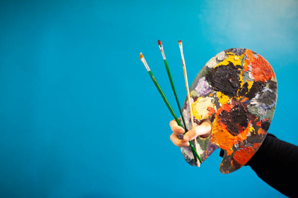 istock woman holding paint brush and pallette on blue background 1085080104