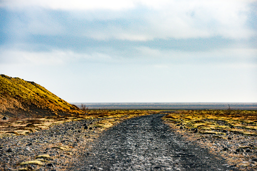 This photograph is of a gravel road curving through the volcanic landscape in Skaftafell, Iceland.