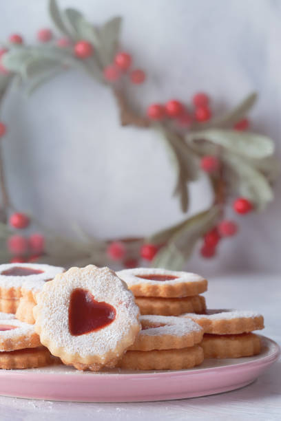 traditionelle weihnachten linzer cookies gefüllt mit roter marmelade auf leuchttisch mit weihnachts-dekorationen - cookie heart shape shortbread christmas stock-fotos und bilder