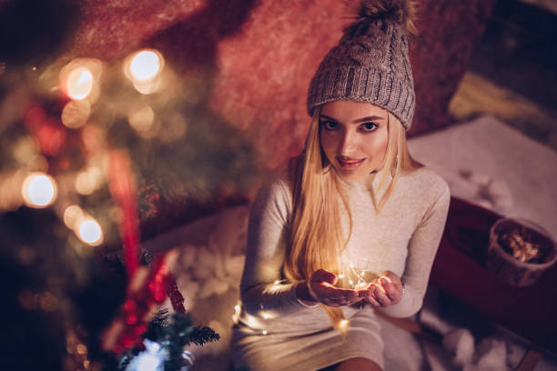 istock Young sensual female sitting by the Christmas tree and fireplace 1085099580