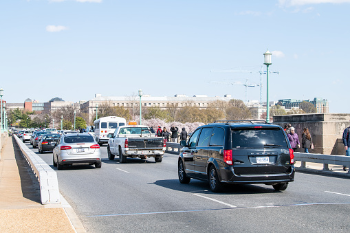 Washington DC, USA - April 5, 2018: People walking by road on Kutz bridge National Mall, cars traffic during cherry blossom, blossoms, sakura festival in spring, springtime