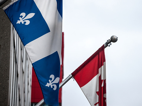 Picture of the flag of quebec standing in front of the flag of Canada in Montreal, Quebec. The flag of Quebec, called the Fleurdelise, was adopted for the province by the government of Quebec, during the administration of Maurice Duplessis.