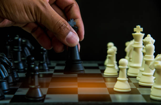 istock The chess board game. A white chess teame and black chess team ,idea for business competition and team work with black blackground 1085114488