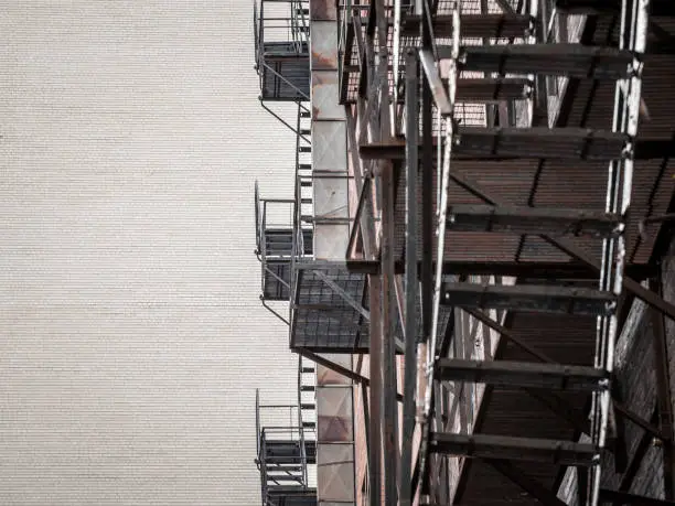 Photo of Fire escape stairs and ladder, in metal, on a typical North American old brick building from Montreal, Quebec, Canada. These stairs, made for emergency, are symbolic of the architecture