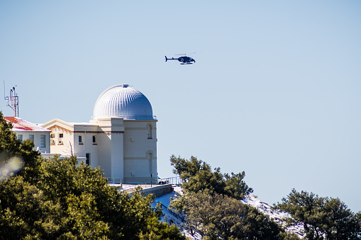 February 27, 2018 San Jose / CA / USA - Fox 2 News helicopter hovers above Lick observatory situated on top of Mt Hamilton on a rare winter day with snow; south San Francisco bay area