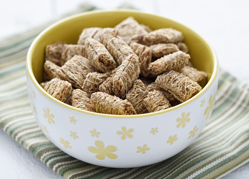 Shreded whole wheat breakfast cereal in a white and yellow bowl