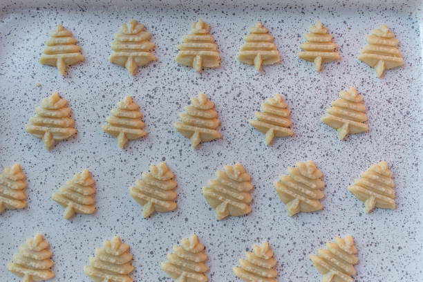 Raw dough Christmas sugar cookies pressed shapes on baking sheet flat lay