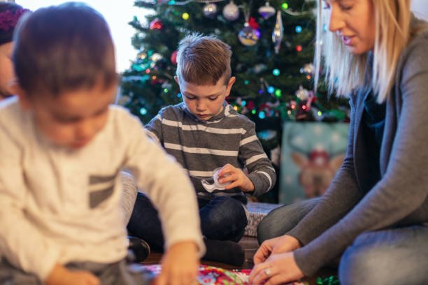 istock Young Family Christmas Preparation Wrapping Presents around Decorated Tree 1085139638