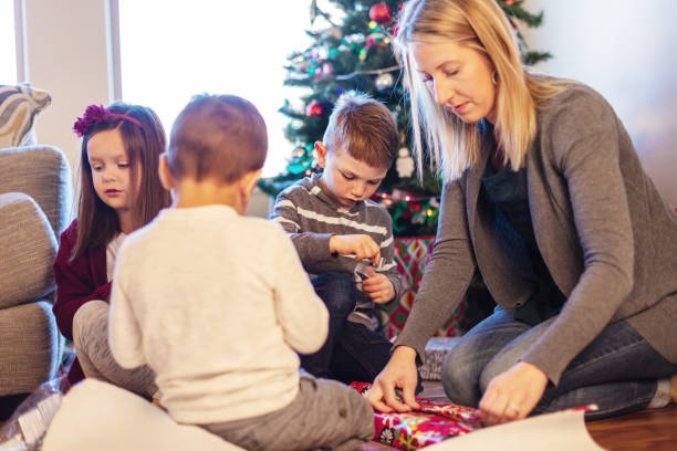 istock Young Family Christmas Preparation Wrapping Presents around Decorated Tree 1085139656