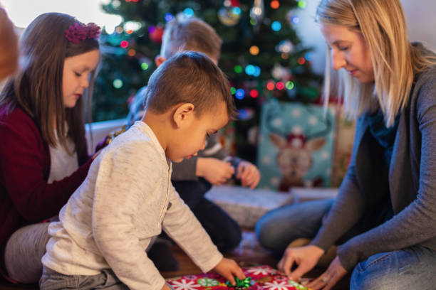 istock Young Family Christmas Preparation Wrapping Presents around Decorated Tree 1085140966