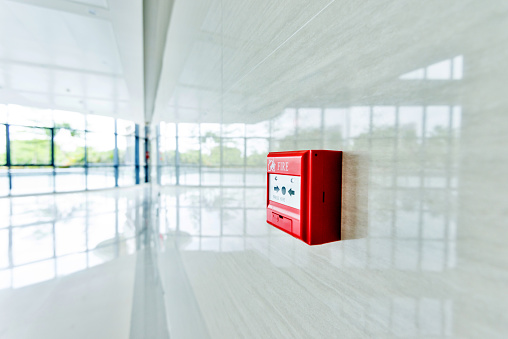 Red fire alarm on white wall.