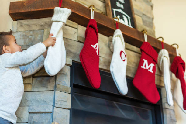 Holiday decorated stone fireplace with three red stockings on the mantle.